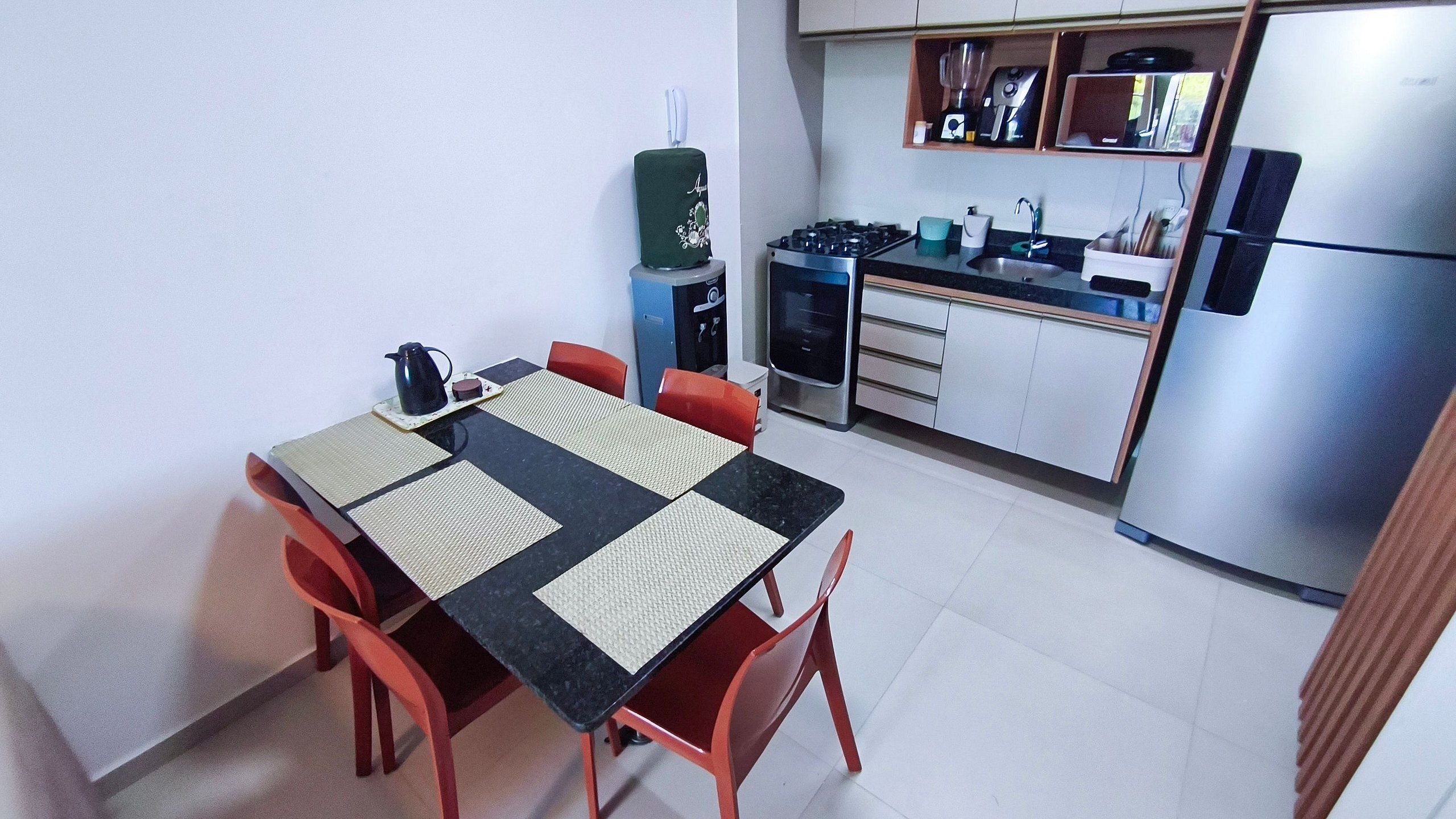 Une cuisine compacte comprenant une table à manger, des chaises et des appareils électroménagers modernes.