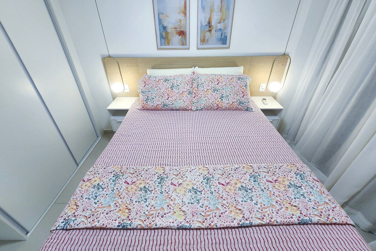 A neatly arranged bedroom with a bed, two bedside tables, and two wall-mounted lamps.