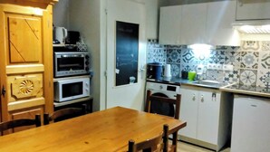 Una cocina compacta con una mesa de comedor de madera, armarios blancos y un salpicadero decorado.