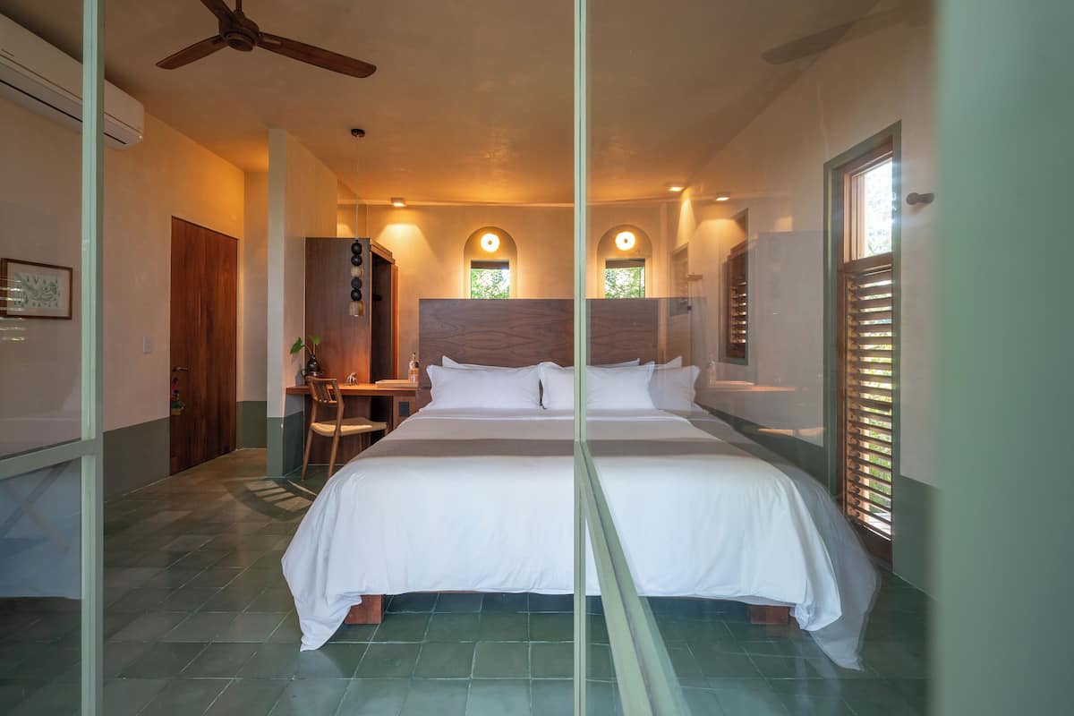 A bedroom with a large bed, a ceiling fan, a desk, and a chair.