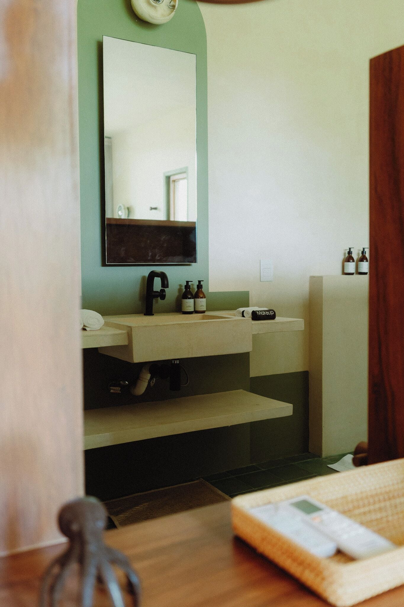 A bathroom with a sink, mirror, and two bottles of liquid soap.