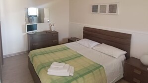 A bedroom with a bed, bedside tables, a dresser, a mirror, and a wall-mounted light fixture. - Adonai House (Sicilia)