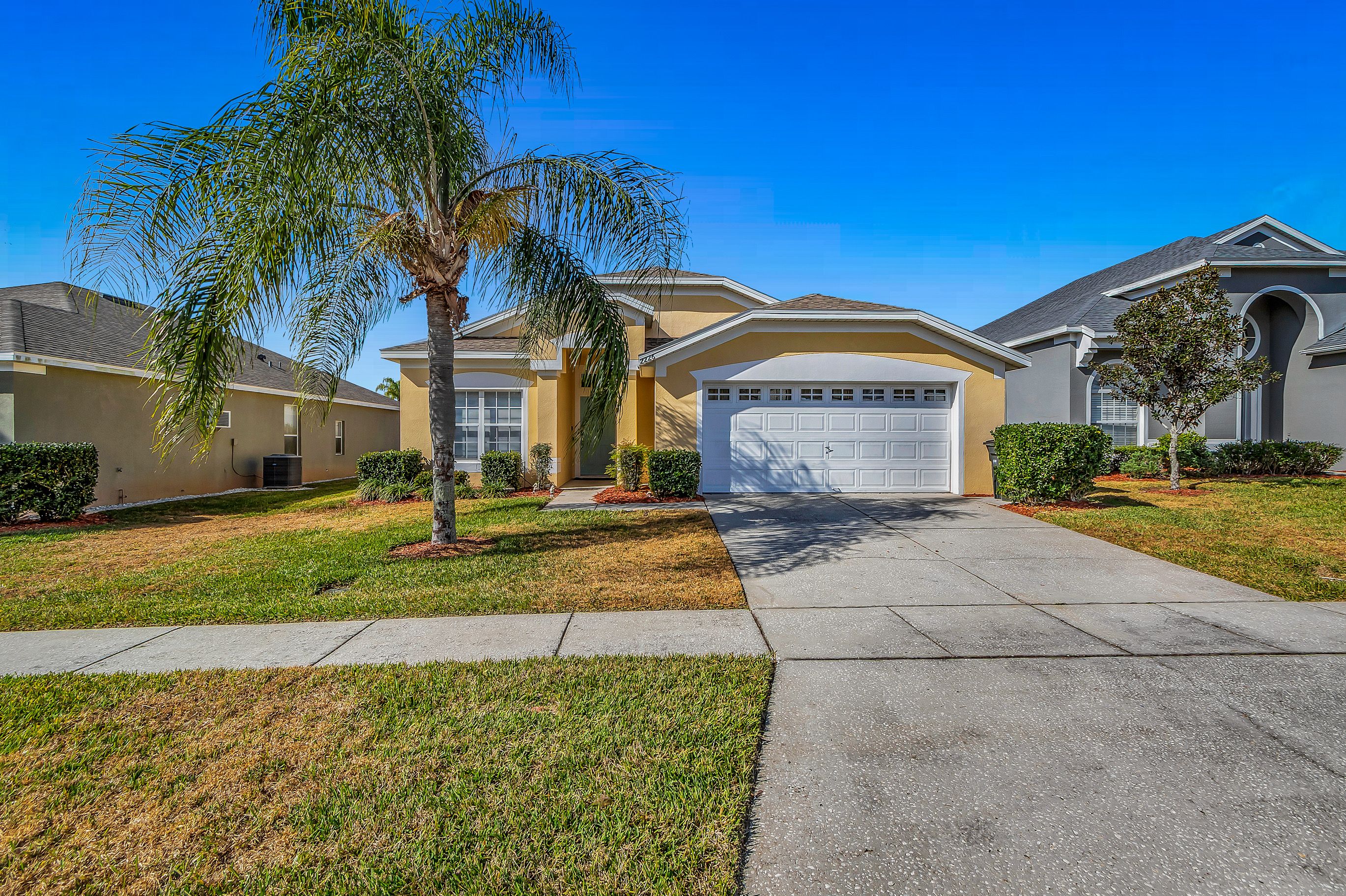 A residential house with a garage, a driveway, and a well-maintained lawn.