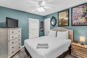 A bedroom with a bed, a dresser, a television, a ceiling fan, and framed posters on the wall. - Disney Getaway - Private Pool & Resort Amenities (Kissimmee)