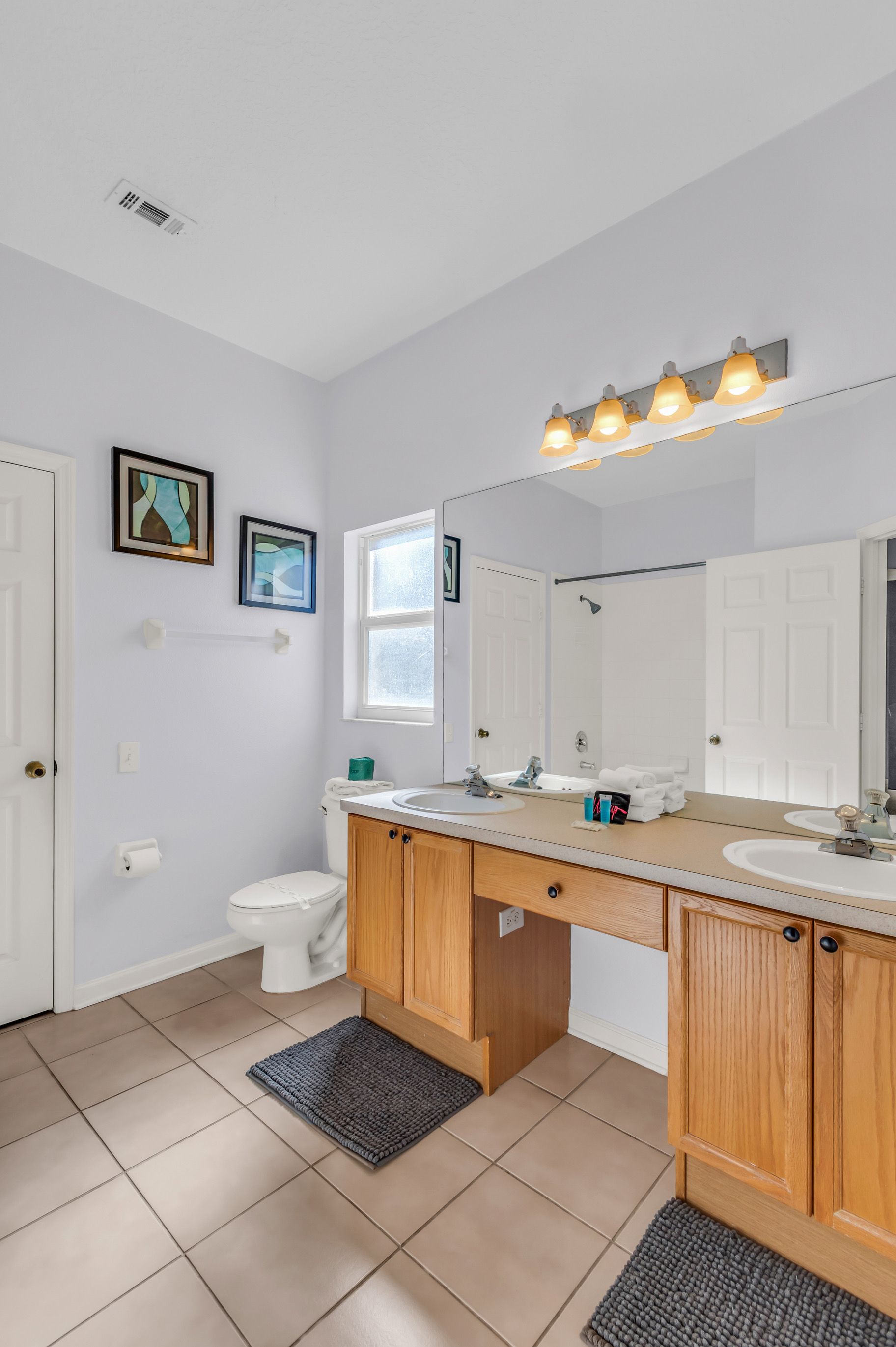A modern bathroom with a double vanity, a large mirror, and a shower.