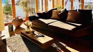Un salon chaleureux avec un canapé, une table basse et une grande fenêtre donnant sur un paysage enneigé.