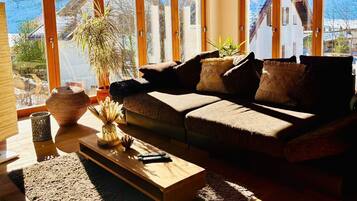 Ein gemütliches Wohnzimmer mit einer Couch, einem Couchtisch und einem großen Fenster mit Blick auf eine verschneite Landschaft.