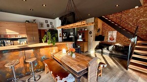 Une cuisine moderne avec un îlot central en bois, des tabourets de bar et une table à manger au style rustique.