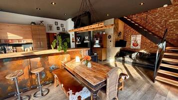 Une cuisine moderne avec un îlot central en bois, des tabourets de bar et une table à manger au style rustique.