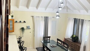 A dining area with a high ceiling, a glass-top table, and black chairs. - Luxury Retreat at Sorrell Ave (St Ann’s Bay)