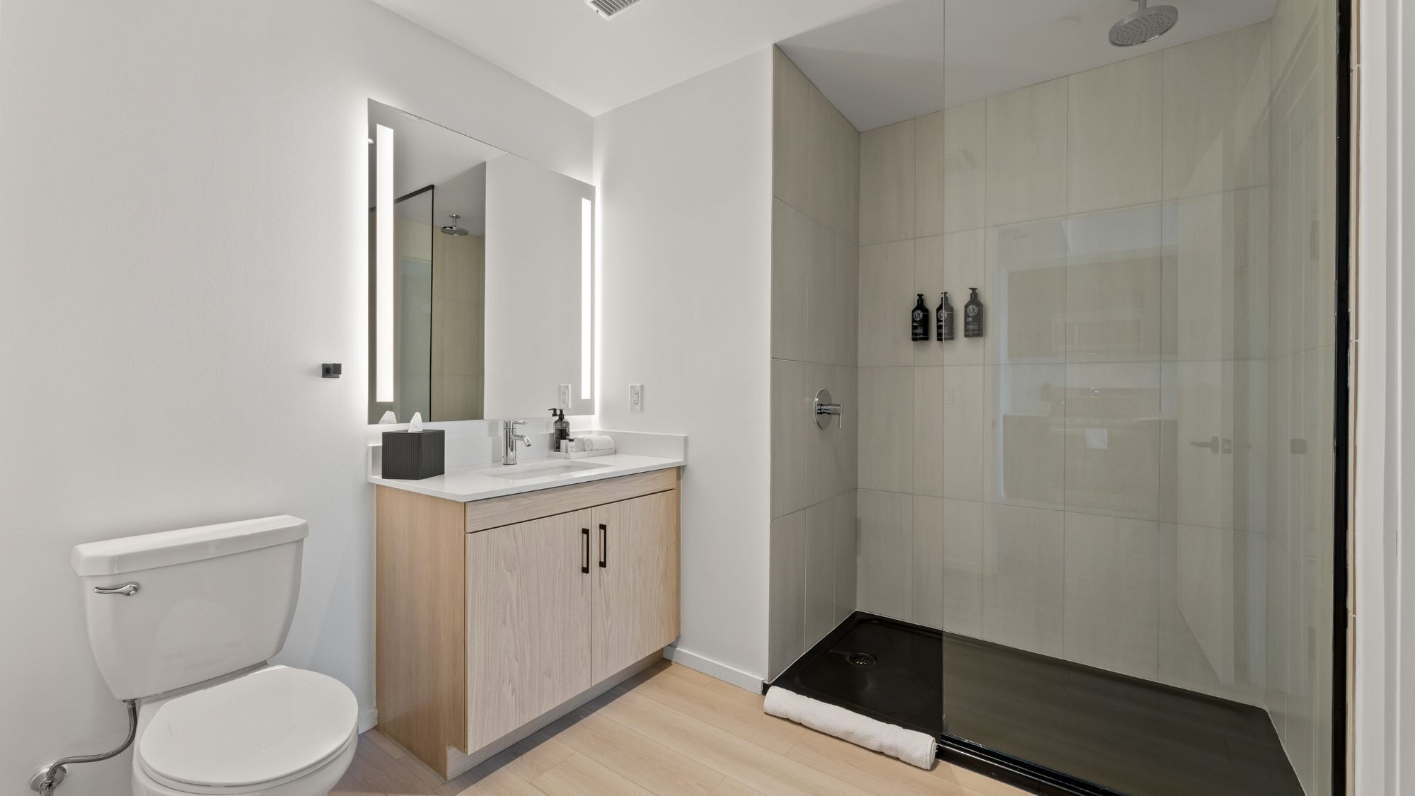Een moderne badkamer met toilet, wastafel, spiegel en douche.