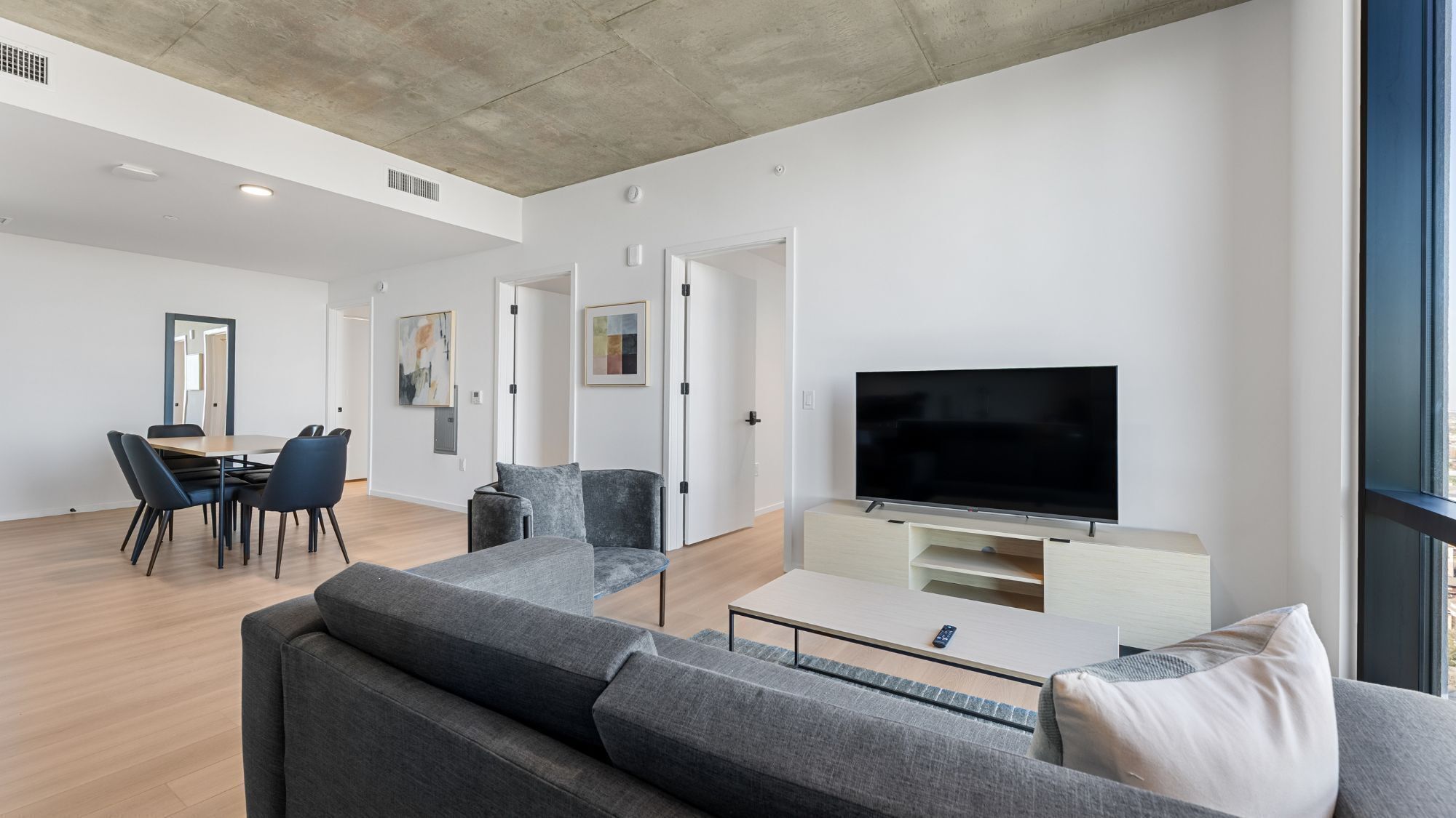 A modern living room with a sofa, TV, and dining area.