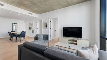 A modern living room with a sofa, TV, and dining area.