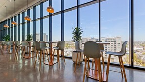 Ein modernes Interieur mit großen Fenstern und mehreren Tischen und Stühlen, die zum Essen bereitstehen.