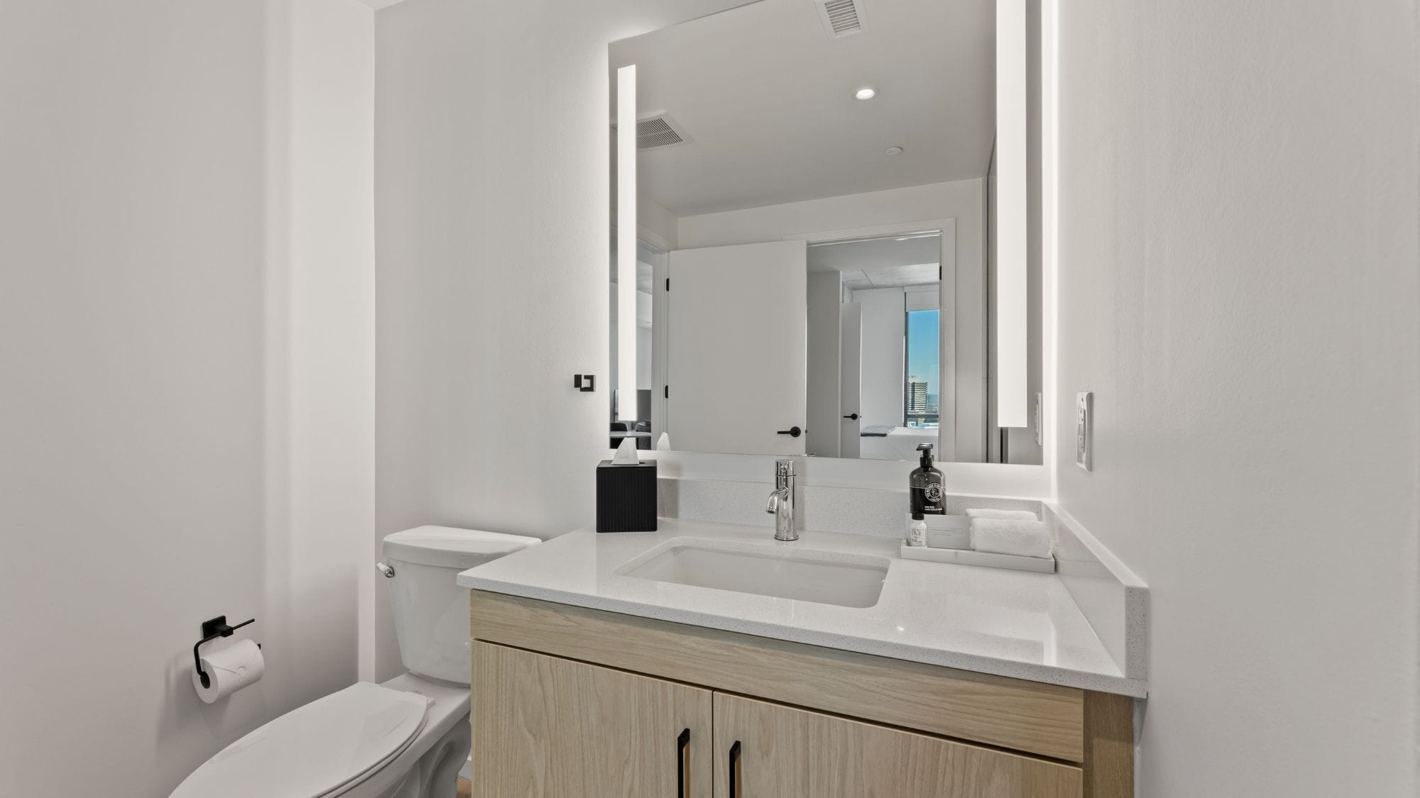 Un bagno moderno con un lavandino bianco, uno specchio e un water.