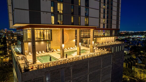 Ein Hochhotel mit Dachpool, mehreren Etagen und Blick auf die Stadt.