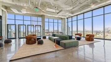 A spacious lounge with large windows, a green sofa, and a view of the cityscape.