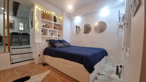 A bedroom with a bed, a dresser, a mirror, and a shelf with decorative items. - Renovated studio with private courtyard in the heart of Béziers (Béziers)