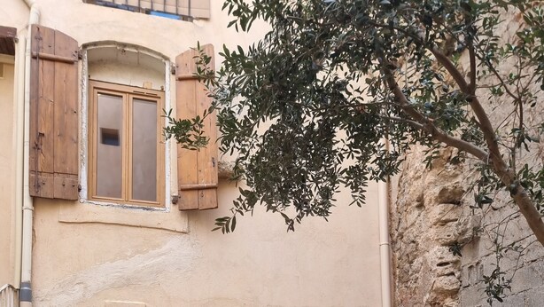 A courtyard with a wooden table and chairs, a potted plant, and a building with a number sign. - Renovated studio with private courtyard in the heart of Béziers (Béziers)