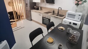 A modern kitchen with white cabinets, a wooden ceiling, and a dining area with a black table and chairs. - Renovated studio with private courtyard in the heart of Béziers (Béziers)