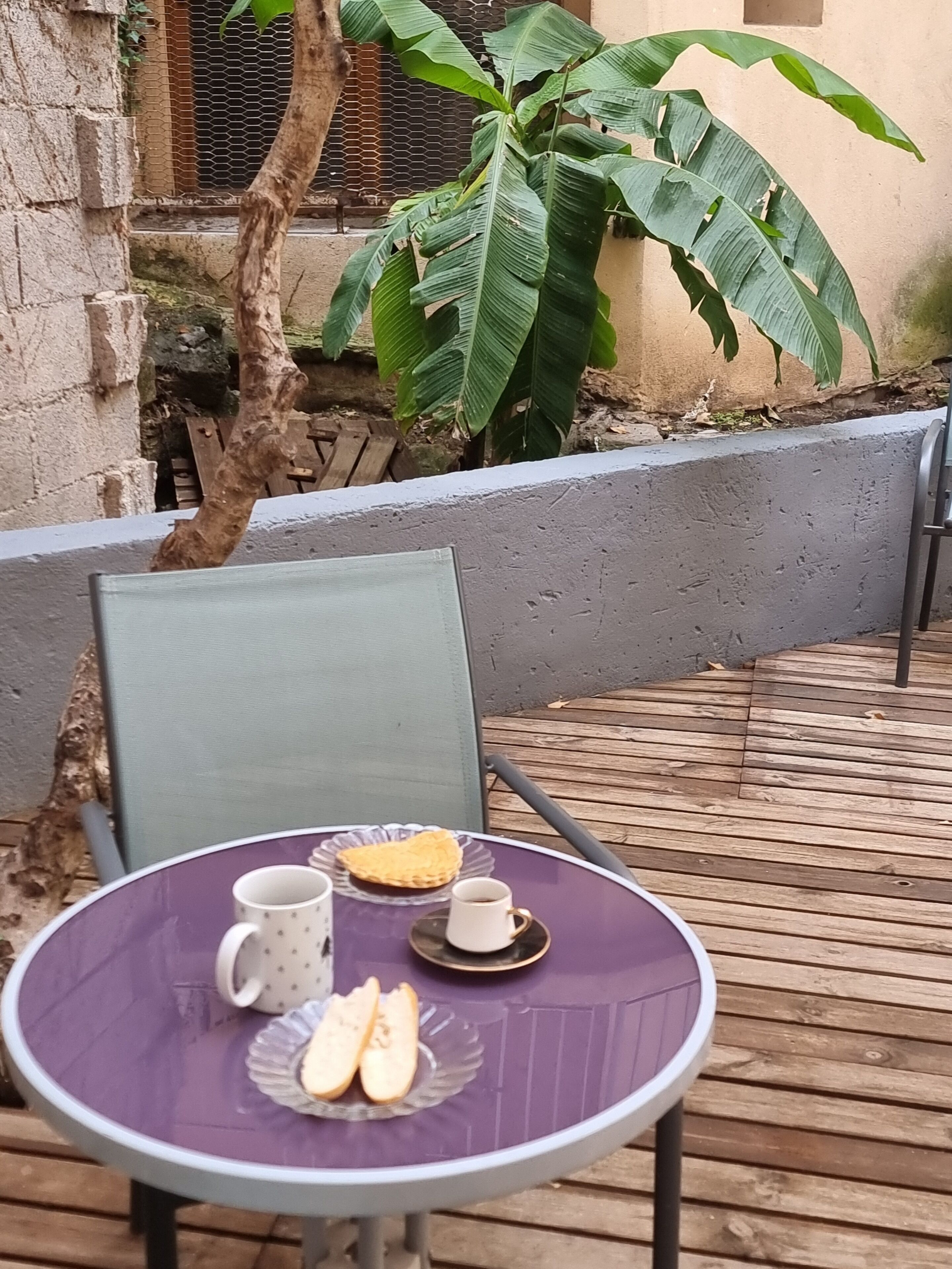 Una mesa redonda con tablero morado y una silla, un plato con un gofre y dos rebanadas de pan, y dos tazas sobre la mesa.