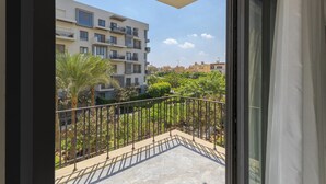 A balcony with a view of a multi-story building, a metal railing, and a clear sky. - 3-bedroom apartment in awesome New Cairo City with AC (New Cairo City)