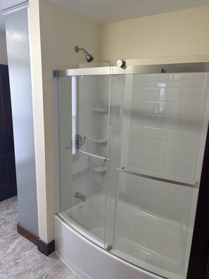 A glass-enclosed shower stall with a handheld showerhead, a glass door, and a tiled wall. - 3 bedroom 2 car garage near Lake Erie and cedar point great for large groups (Clyde)
