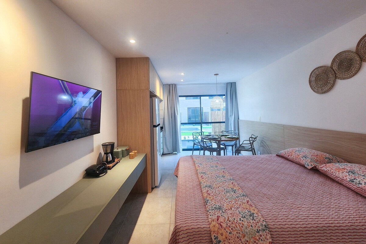 Una habitación de hotel moderna con cama, televisión, escritorio y zona de comedor.