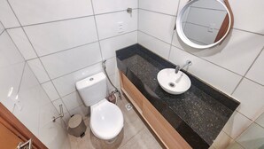 A bathroom with a toilet, sink, mirror, and tiled walls. - Max Carneiros Suites - Praia dos Carneiros by CTA (Tamandaré)