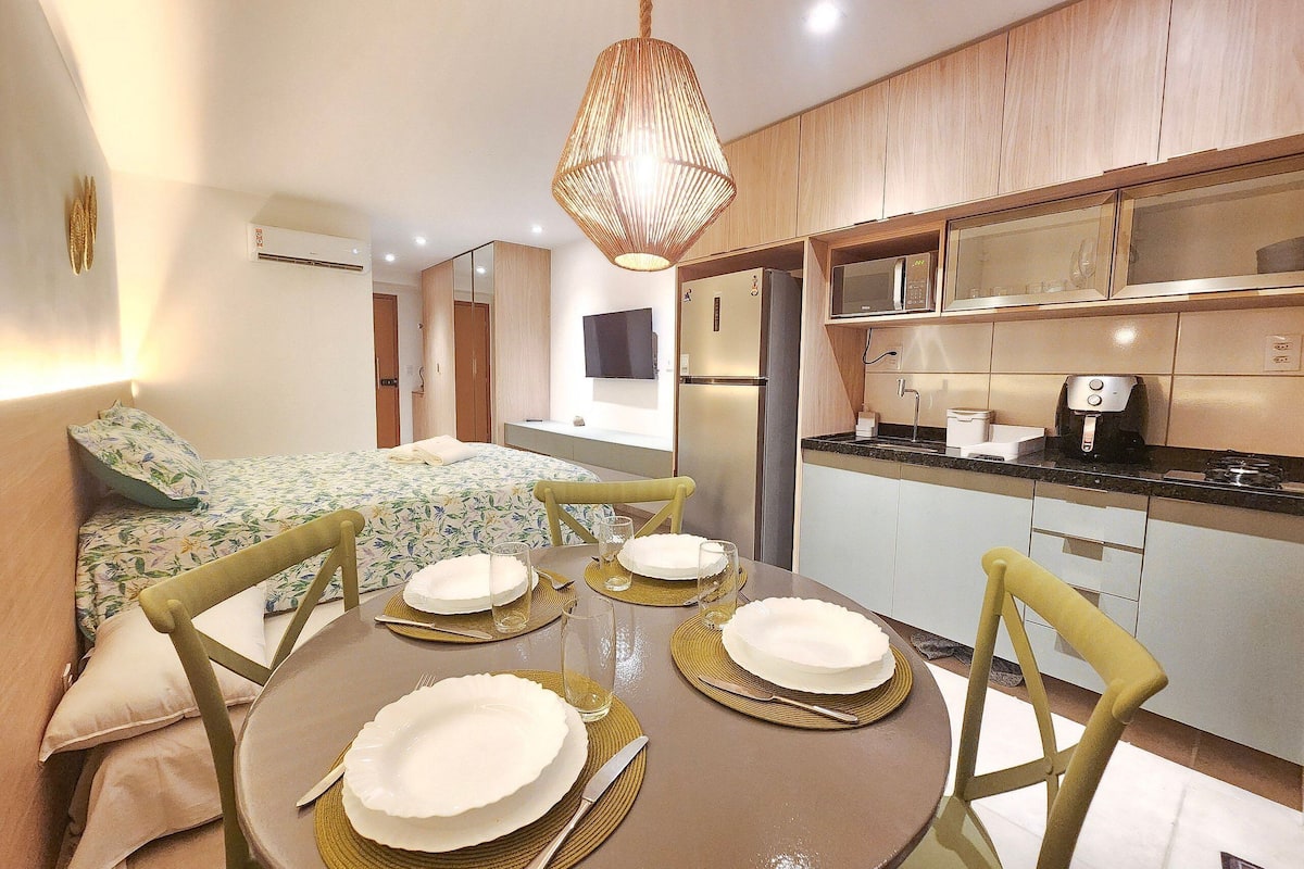 A modern kitchen with a microwave, stove, and refrigerator. There is a dining table set with plates and cutlery.