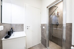 Un baño moderno con ducha, lavamanos y espejo.