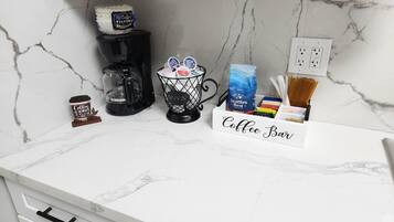 A kitchen counter with a coffee maker, a coffee cup, a coffee filter basket, and a coffee bar sign.