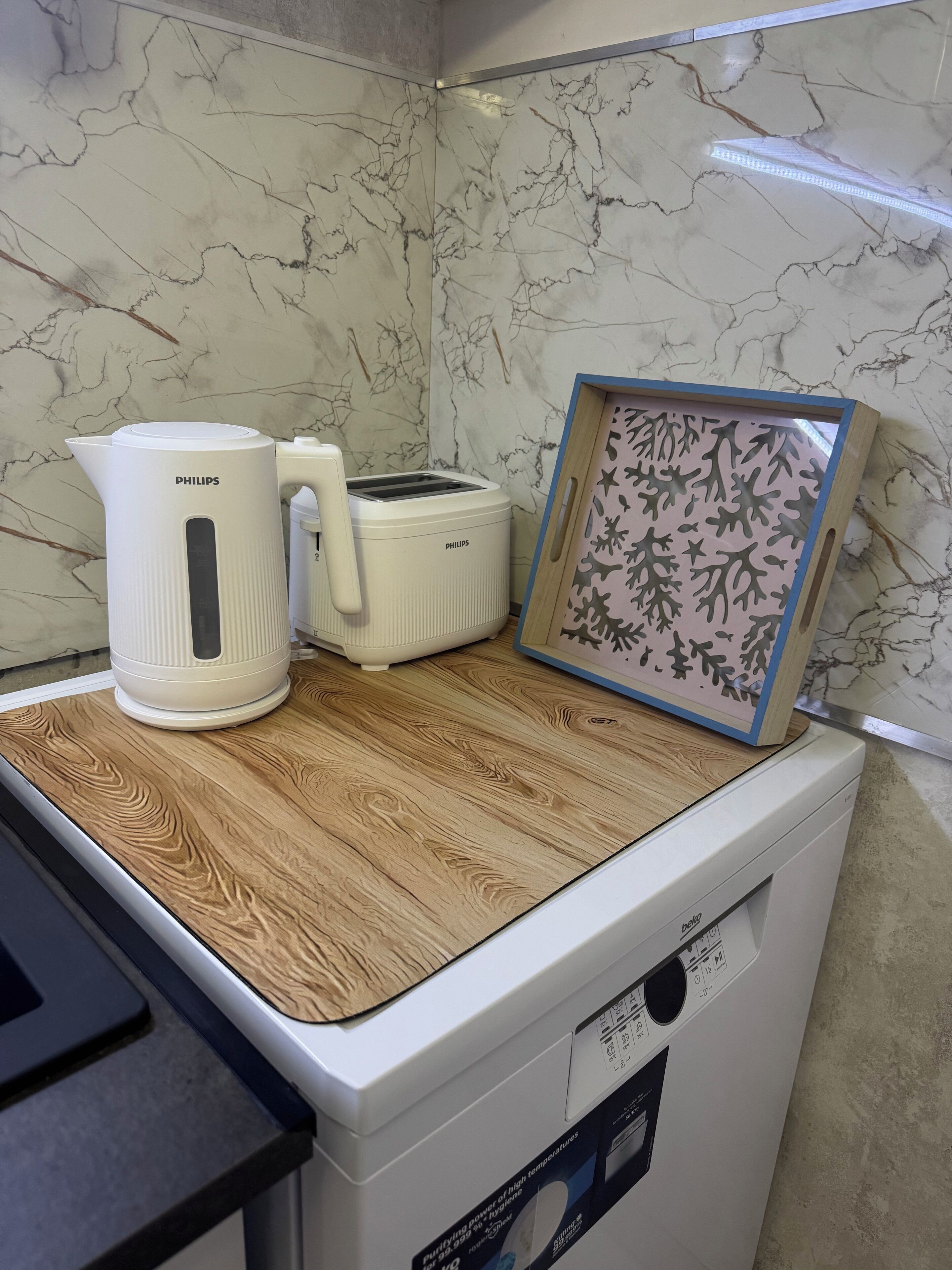 A kitchen with a marble backsplash, a coffee maker, a toaster, and a framed picture on a wooden countertop.