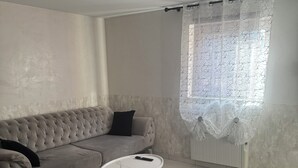 Un salon avec un canapé gris, une table basse blanche et un tapis gris.