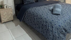 Une chambre à coucher avec un lit, une table de chevet, un miroir et une lampe.