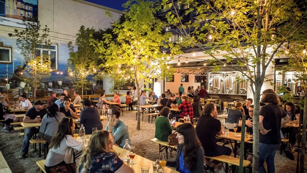 An outdoor dining area with tables and chairs, surrounded by trees and string lights. - Trendy Roncesvalles Village. Just steps to shopping, dining, Lake Ontario (Toronto)