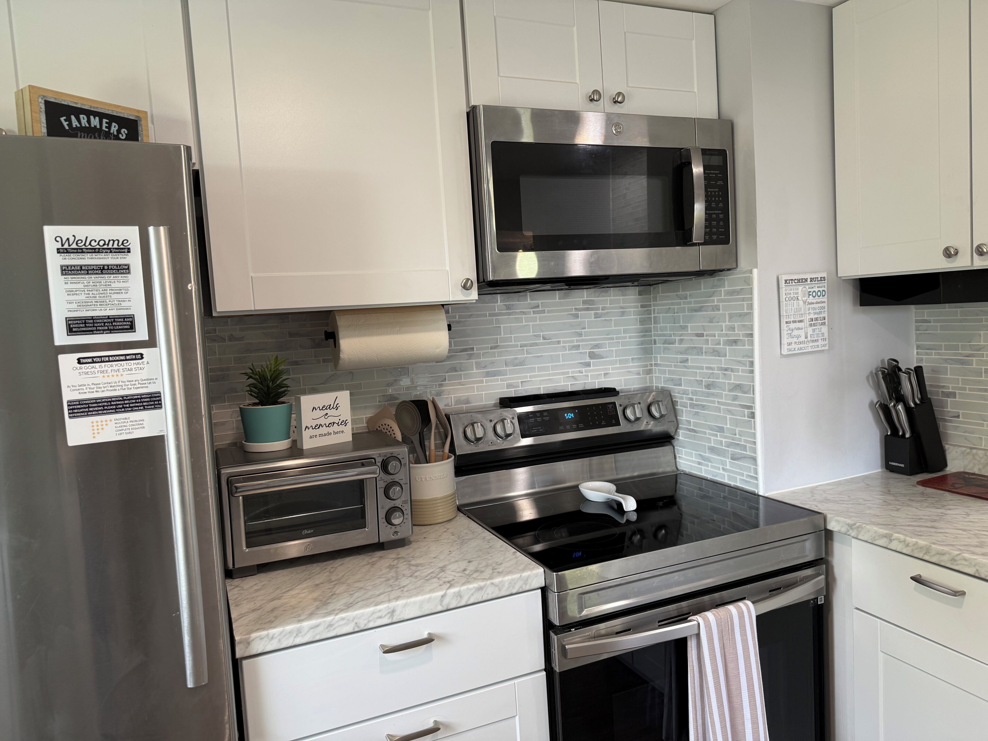 A modern kitchen with stainless steel appliances, white cabinets, and a tiled backsplash.