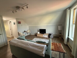 A modern living room with a sofa, a TV, a wooden coffee table, and a lamp.