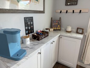 Eine Küche mit einer Keurig-Kaffeemaschine, einer Kaffeekarte, einer Kaffeebar und einem Schild mit der Aufschrift 'Hello Coffee'.