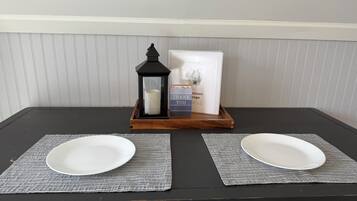 A table with two white plates on placemats, a black lantern, and a welcome sign.