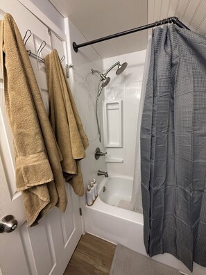 Ein Badezimmer mit Badewanne, Dusche und Handtuchhalter mit Handtüchern.