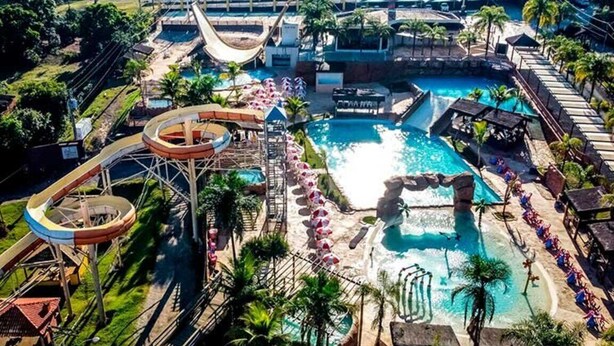 Een waterpark met een groot zwembad, glijbanen en een golfslagmachine.