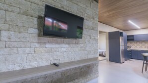 Een moderne keuken met een stenen muur, een flatscreen televisie en een ingebouwde bank.
