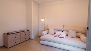 Ein moderner, minimalistischer Raum mit einer Couch, einem Beistelltisch und einem Schrank.