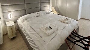 Ein modernes Schlafzimmer mit einem großen Bett, Nachttischlampen, einem Nachttisch und einem Sessel.