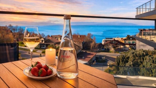 Ein Balkon mit Tisch, einer Weinflasche, einem Weinglas und Erdbeeren.