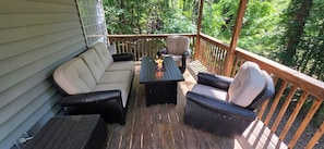 Una terraza techada con un sofá, dos sillones y una mesa.