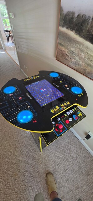 Une table d’arcade avec le jeu Pac-Man, dotée d’un écran numérique, d’un joystick et de boutons.