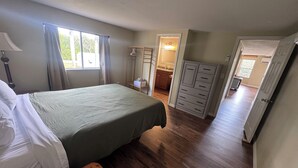 Ein Schlafzimmer mit einem Bett, einer Holzbank, einem Schminktisch und einem begehbaren Kleiderschrank.