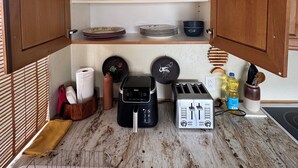 Eine kompakte Küche mit Holzschränken, einer eingebauten Mikrowelle, einem Toaster und einem Spülbecken.